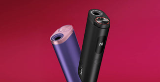 Dos elegantes dispositivos electrónicos, uno morado con la parte superior rosa y otro negro con una pantalla circular en la que se lee hi, se muestran sobre un fondo rosa vibrante.