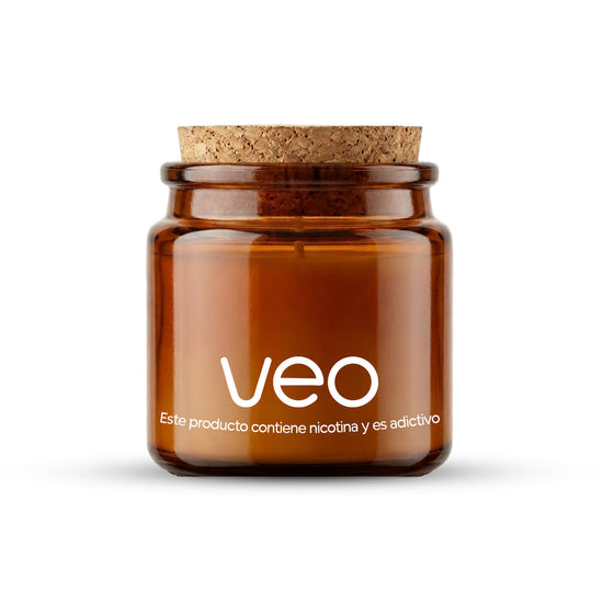 Un pequeño tarro de vidrio ámbar con tapa de corcho etiquetado veo™ Vela de vainilla. Texto debajo: Este producto contiene nicotina y es adictivo. Disfruta envío gratis y oferta 50€ por tiempo limitado.