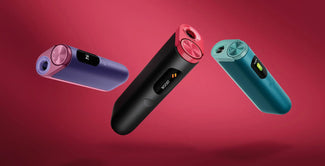 Tres elegantes y coloridos inhaladores electrónicos (morado, negro con toques rosas y verde azulado) destacan sobre un fondo rojo, cada uno de ellos con una pantalla digital y una boquilla circular.