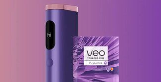 Un elegante dispositivo de color púrpura con una pequeña pantalla en la que se muestra "hola" se sitúa junto a un paquete de productos sin tabaco Veo de color púrpura con la etiqueta Purple Click sobre un fondo de degradado púrpura.