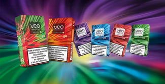 Cinco coloridas cajas de productos de nicotina sin tabaco Veo se muestran sobre un fondo multicolor vibrante y arremolinado. Cada caja contiene advertencias sanitarias en español sobre la nicotina y sus riesgos para los no fumadores y los ex fumadores.